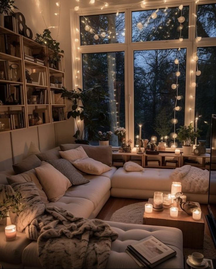 a living room filled with lots of furniture and candles in front of a large window