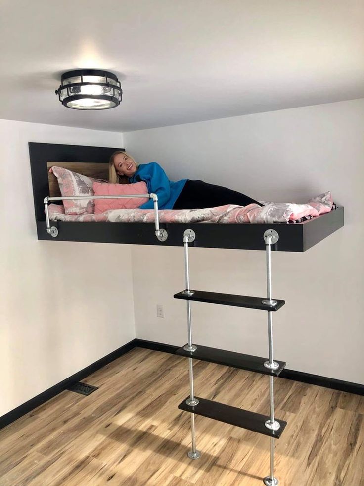 a person laying on top of a bunk bed in a room with wooden floors and white walls