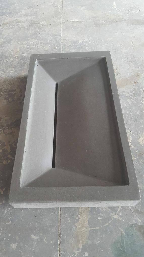 a gray square shaped object on the ground with one section missing from it's base