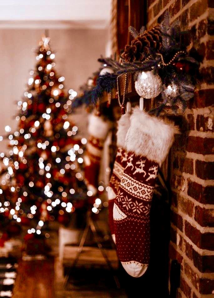 stockings hanging on the wall next to a christmas tree in a room with brick walls