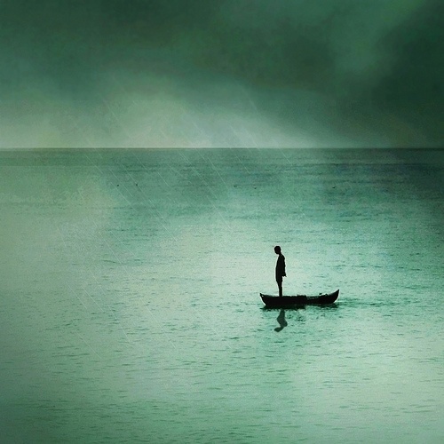 a man standing on top of a boat in the middle of a body of water