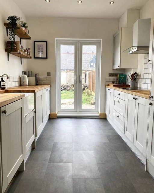 a kitchen with white cabinets and gray flooring