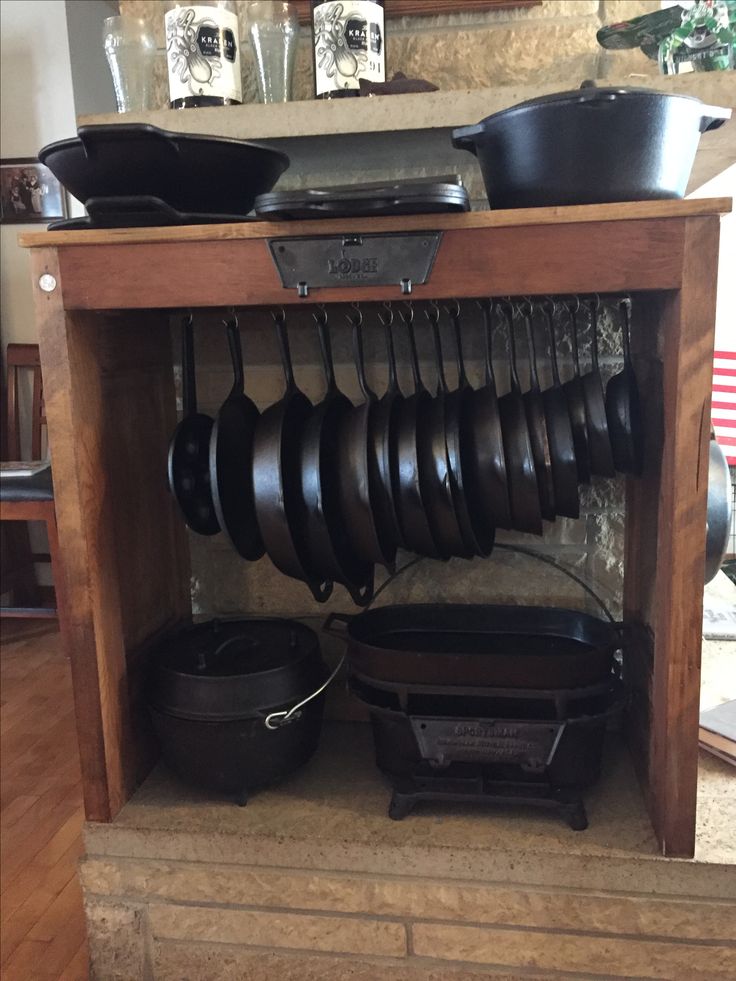 pots and pans are hanging from the rack in this kitchen cabinet with an open drawer