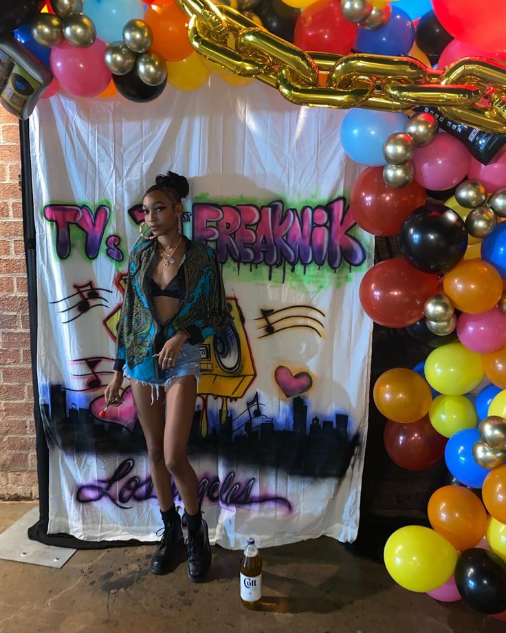 a woman standing in front of a backdrop with balloons