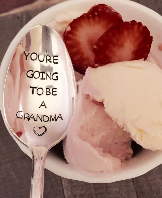 a bowl filled with ice cream and strawberries on top of a wooden table next to a spoon that says, you're going to be a grandma