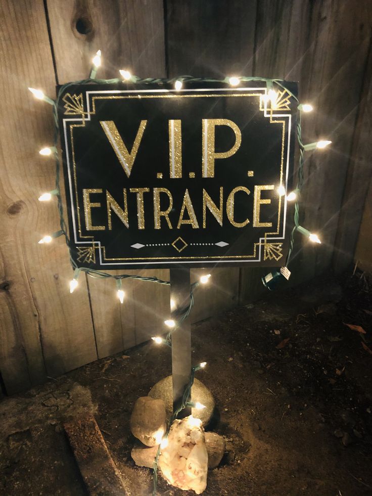 a lit up sign that says vip entrance on it's post in front of a wooden fence