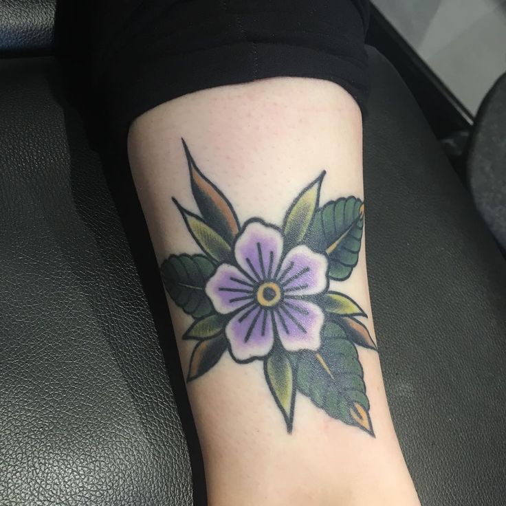 a woman's foot with a flower tattoo on the side of her leg,