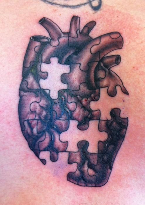 a heart shaped puzzle piece tattoo on the back of a man's shoulder and chest