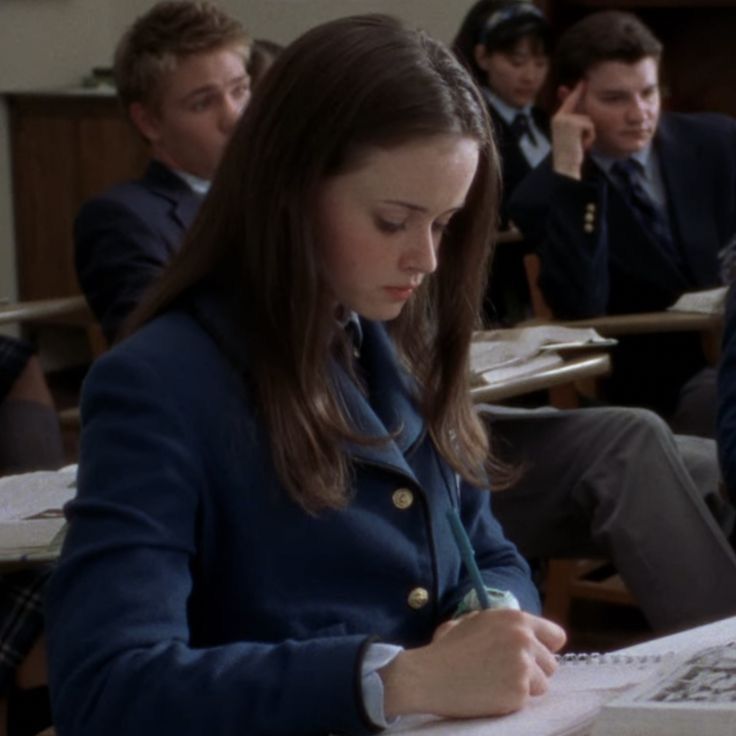 a group of people sitting at desks with books and papers in front of them