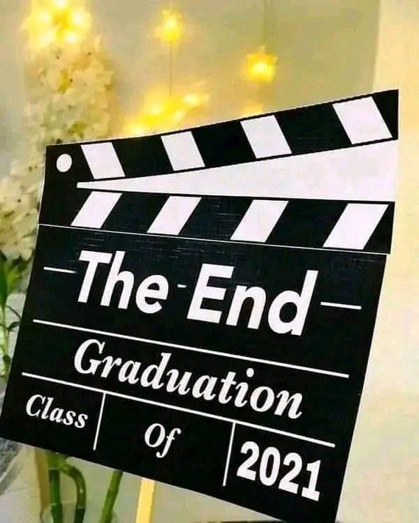 a black and white sign that says the end graduation class of 2021 with flowers behind it