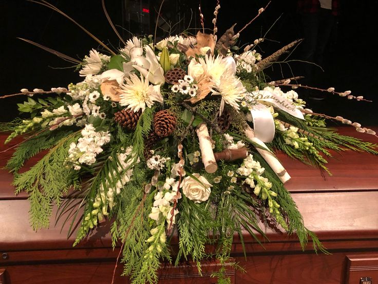 an arrangement of flowers and greenery on top of a piano