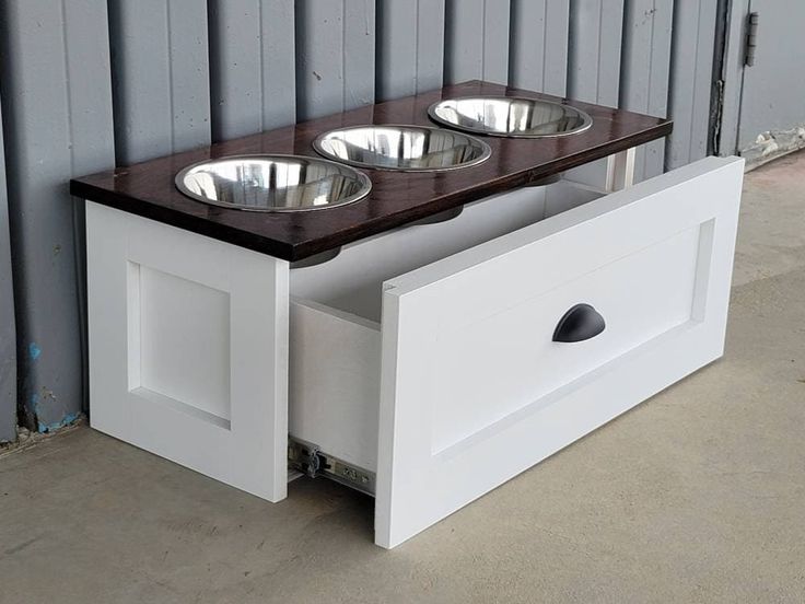 a dog bowl stand with three bowls on it's top and one drawer open