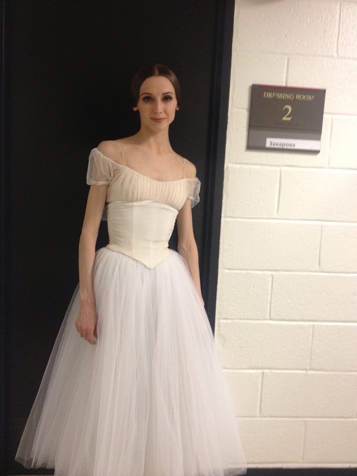 a woman in a white dress standing next to a door