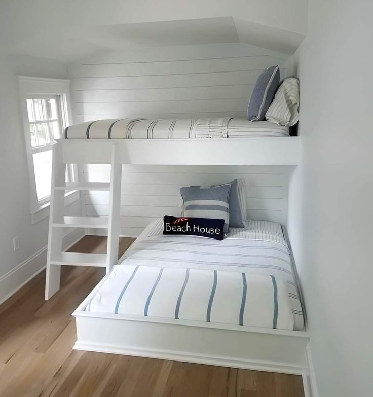 a bunk bed in a room with white walls and wood flooring on the bottom level