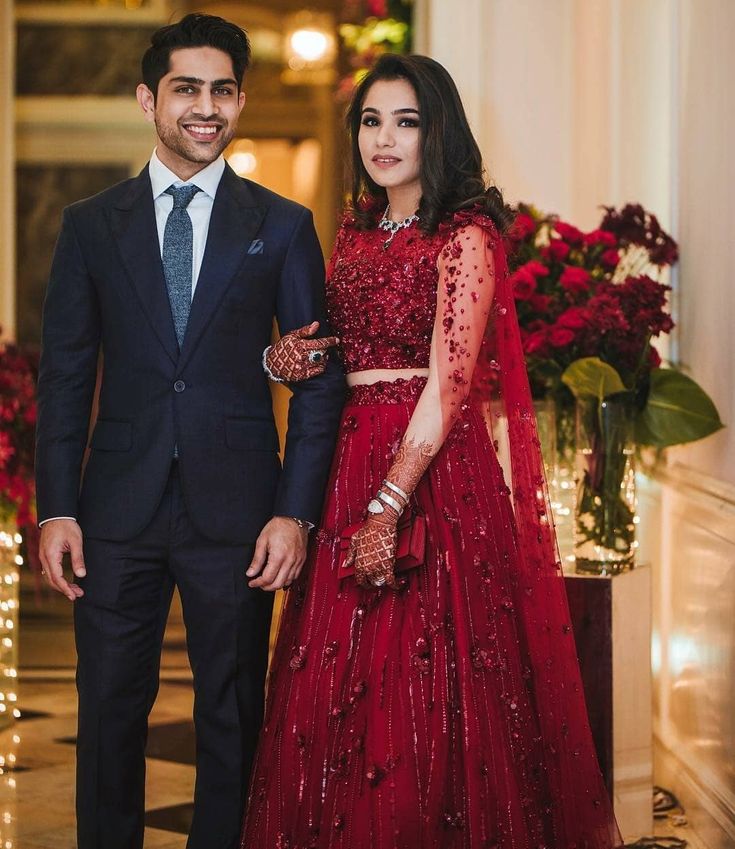 a man and woman standing next to each other in formal wear, dressed in red