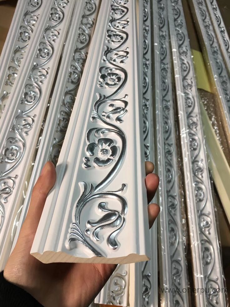 someone is holding up some decorative molds to paint them in white and silver colors