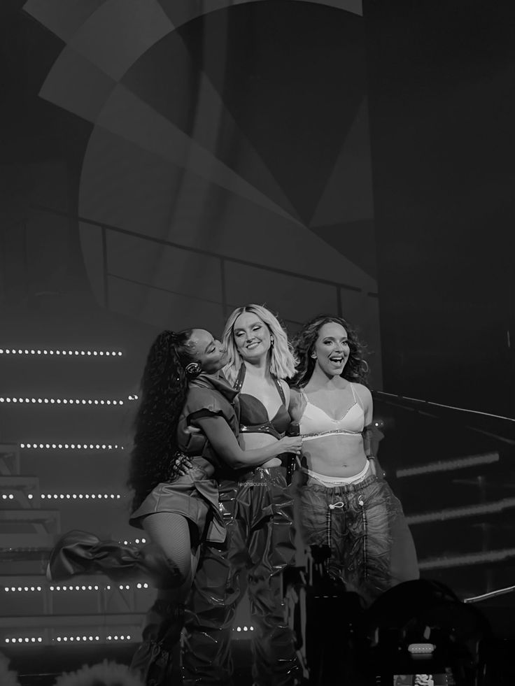 three women standing on stage with their arms around each other