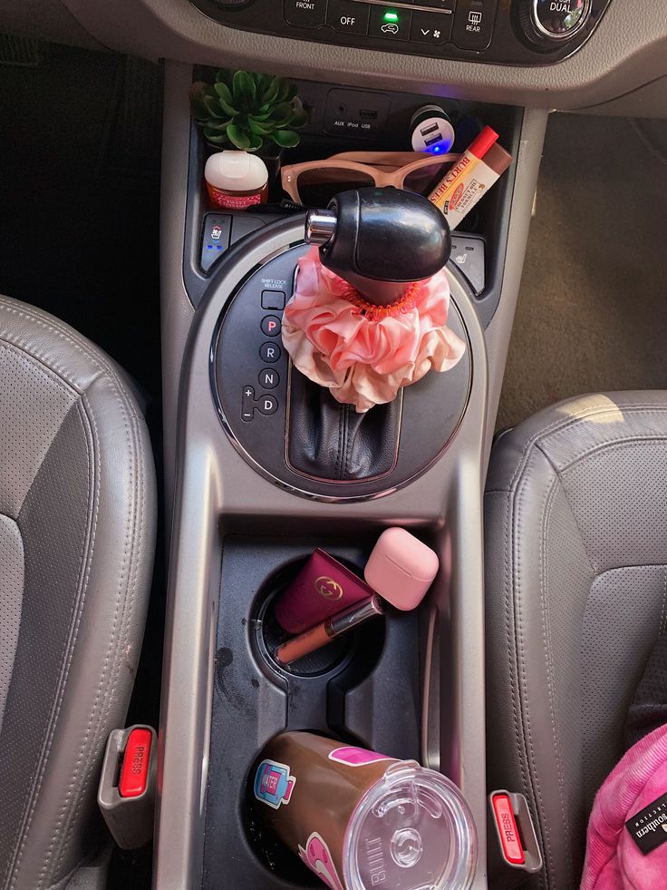 the interior of a car with various items in it's center console and cup holder