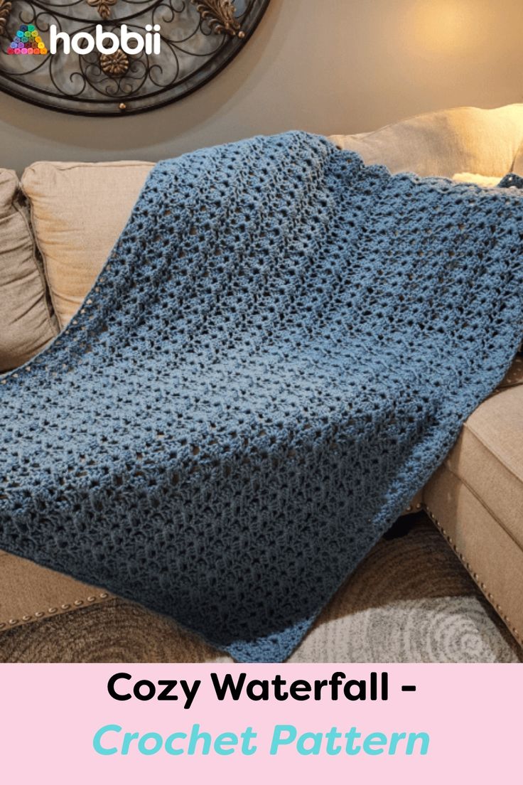 a blue crocheted blanket sitting on top of a couch next to a clock