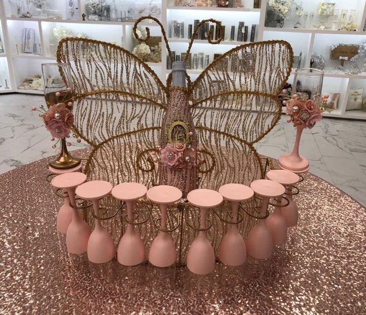 a pink table topped with lots of vases and a large butterfly decoration on top of it