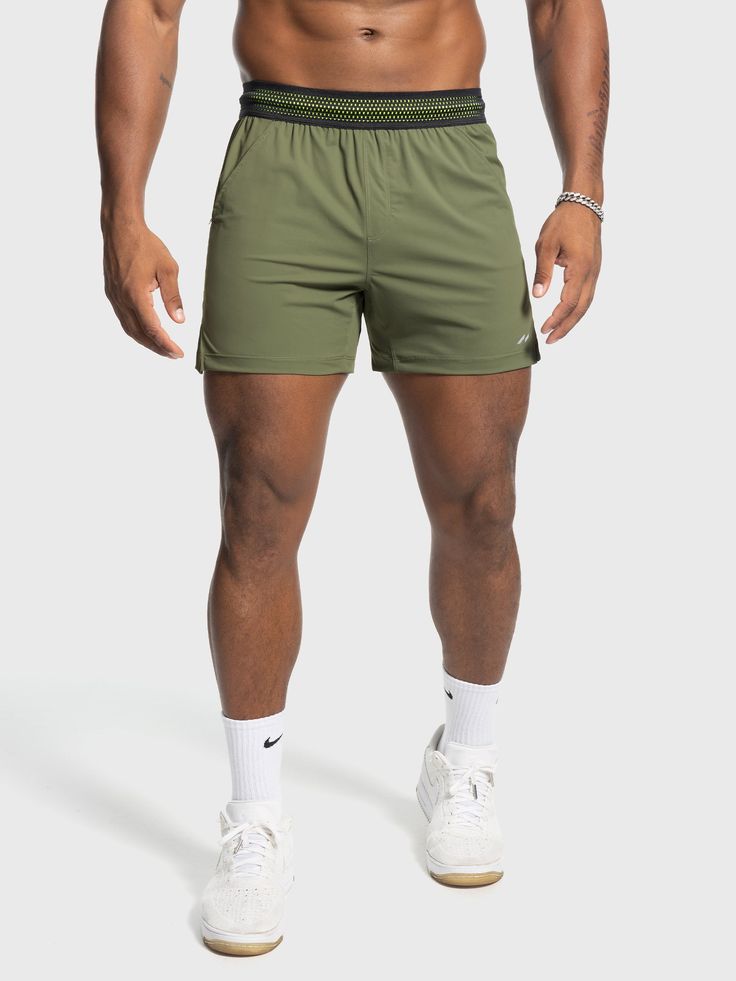 a man in green shorts and white socks posing for the camera with his shirt off