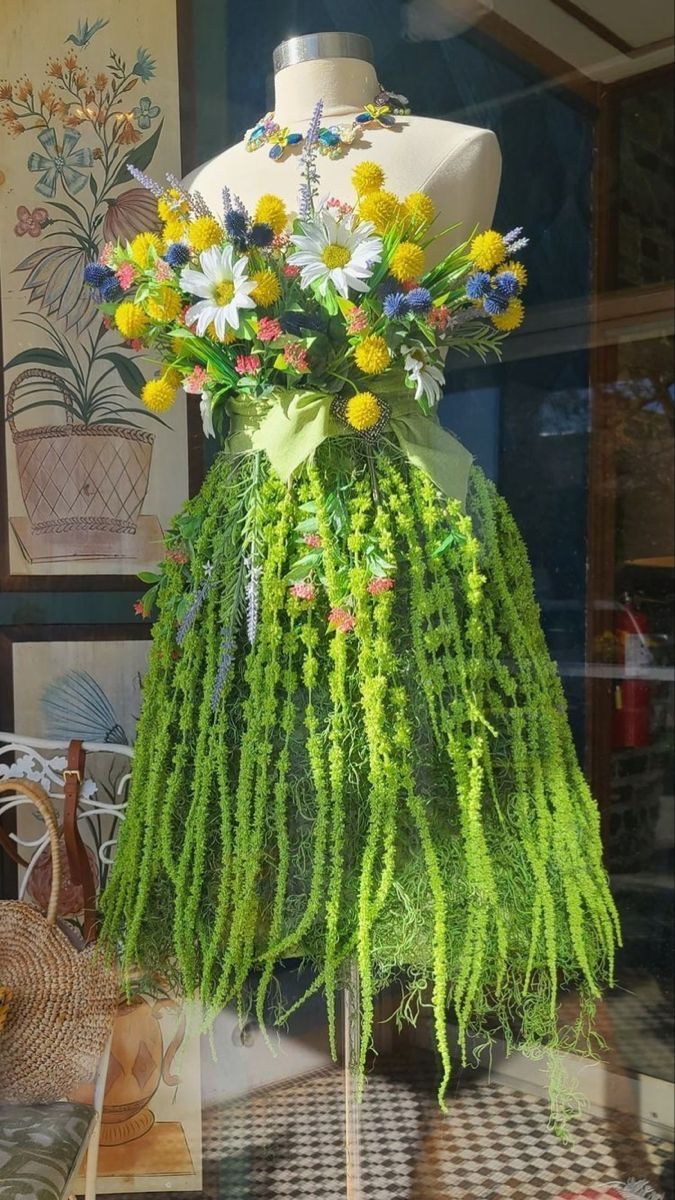 a mannequin is covered in flowers and grass