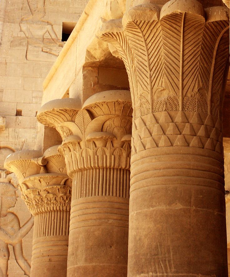 some very tall pillars in front of a building with carvings on the walls and ceiling