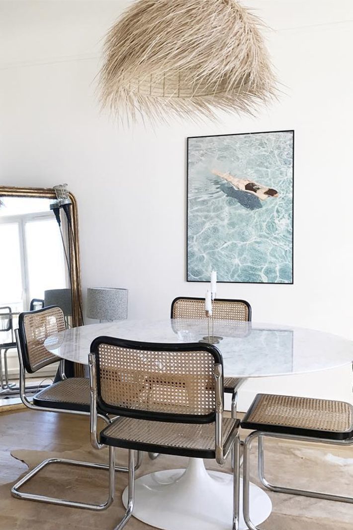 a dining room table with chairs and a painting on the wall