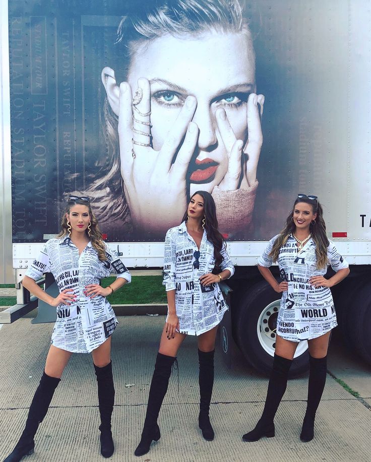 three beautiful women standing in front of a large truck with advertisement on it's side