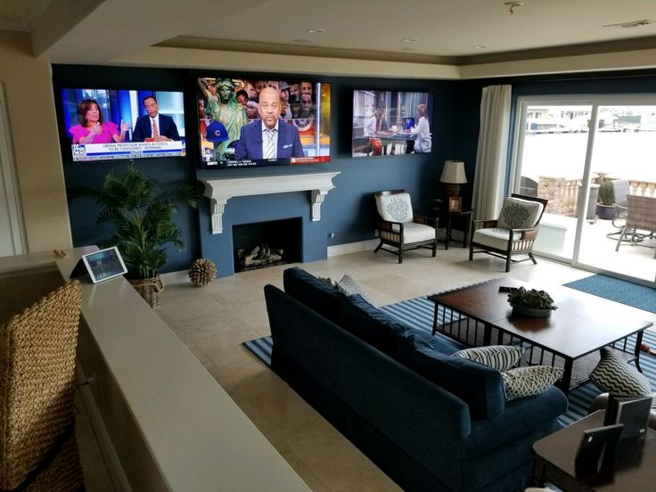 a living room filled with furniture and flat screen tvs on the wall next to a fire place