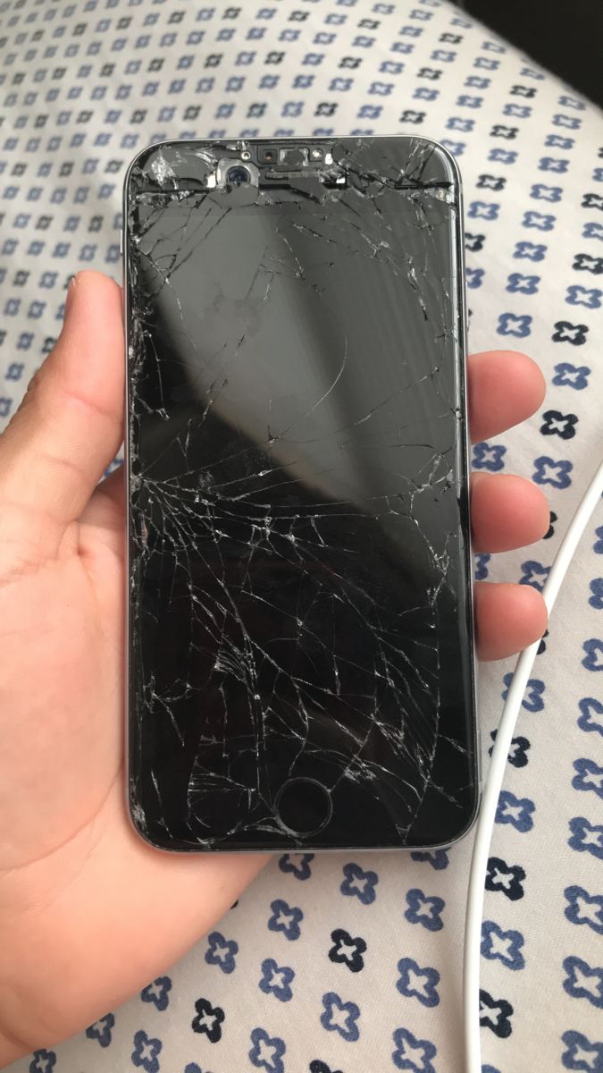 a broken cell phone in the palm of someone's hand on a patterned surface