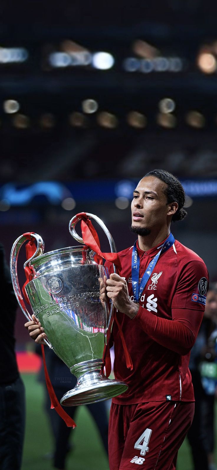 a man holding a trophy on top of a soccer field