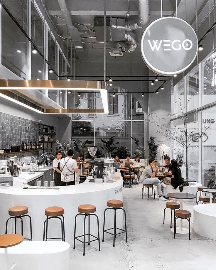 the interior of a restaurant with people sitting at tables and stools in front of it