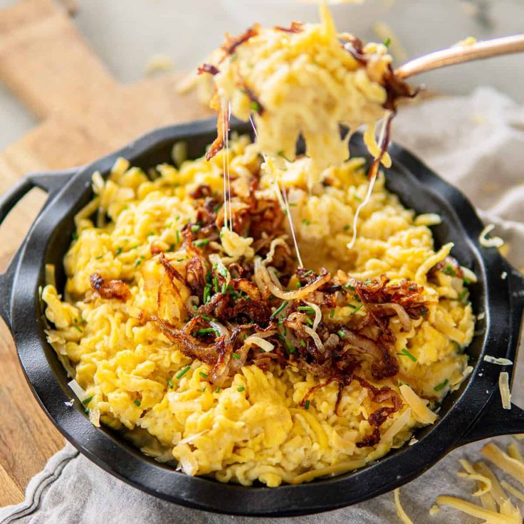 a skillet filled with rice and vegetables on top of a wooden cutting board