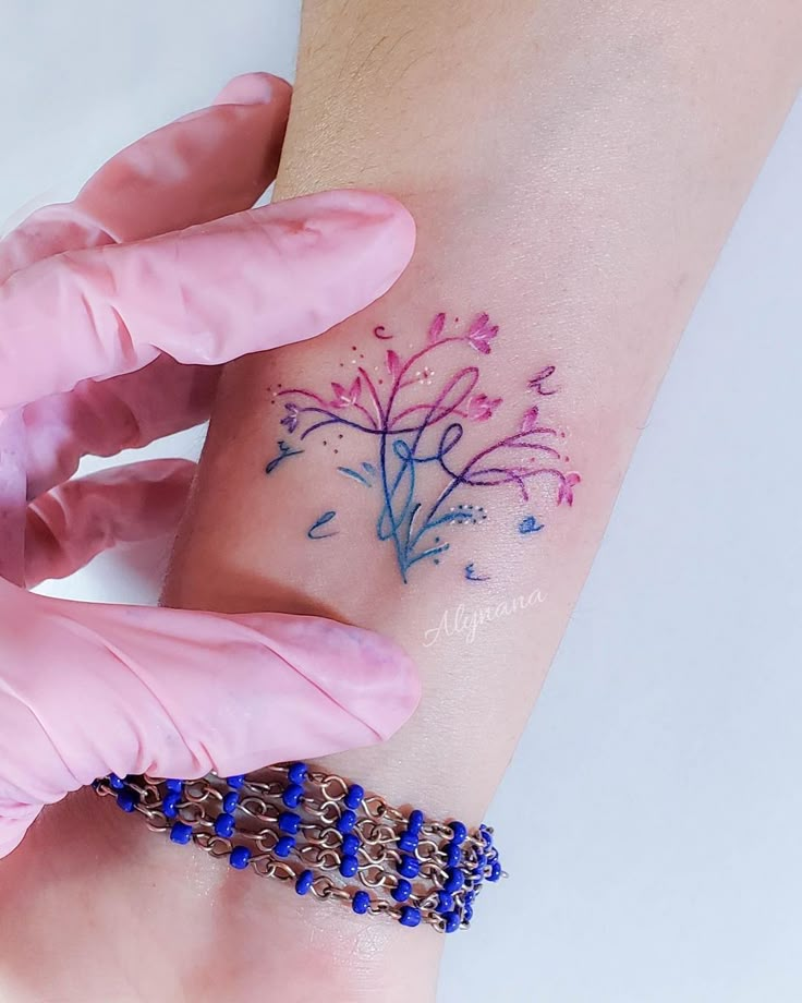 a woman's arm with a tattoo on it that has blue and pink flowers