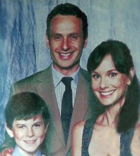 a man and woman standing next to each other in front of a blue wall with a photo on it