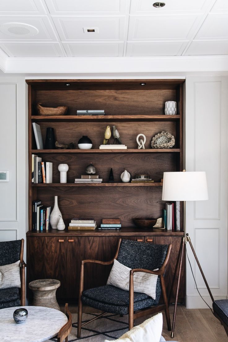 a living room with two chairs and a book shelf in the corner on the wall