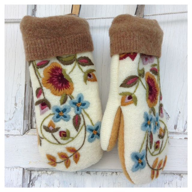 a pair of white mittens with flowers on them hanging from the side of a door