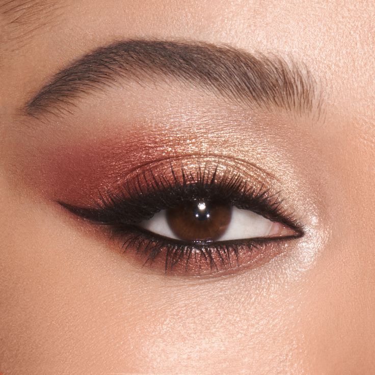 a woman's eye with red and gold makeup on her eyeshadow, close up