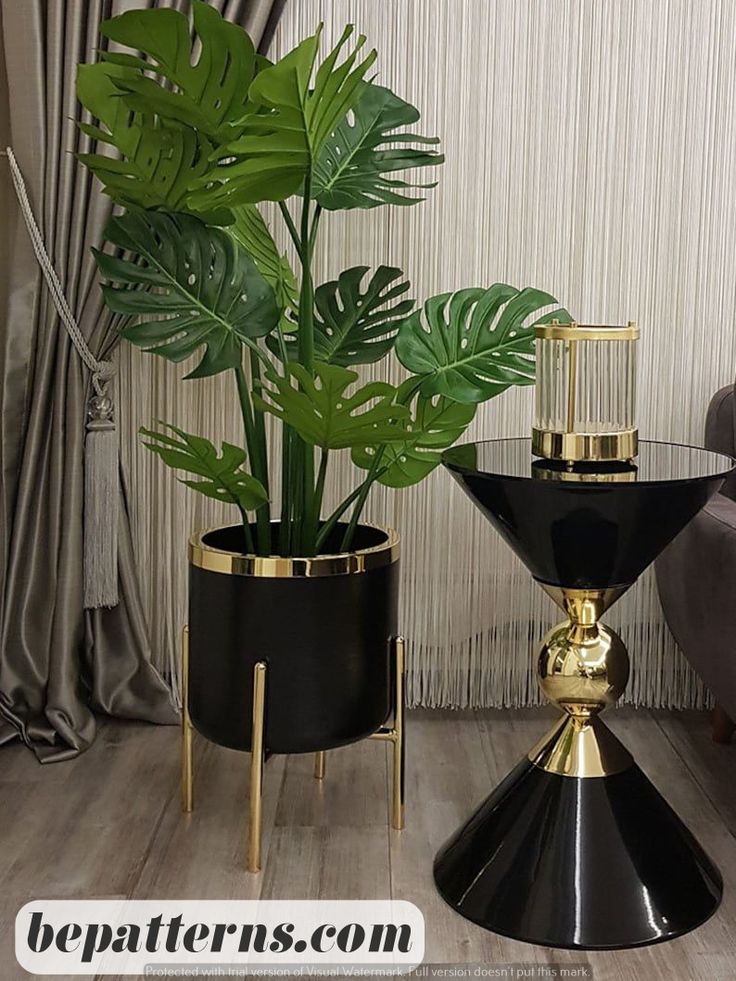 two black and gold vases with plants in them on a wooden floor next to a couch