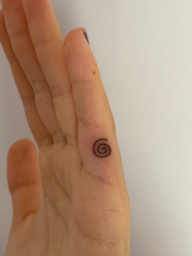 a person's hand with a small tattoo on the middle of their left thumb