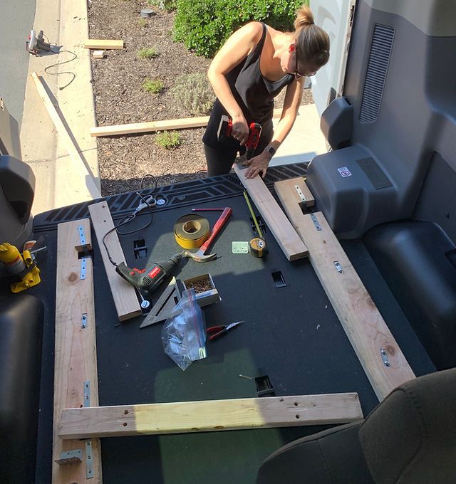 a woman is working on something in the back of a truck that's being built