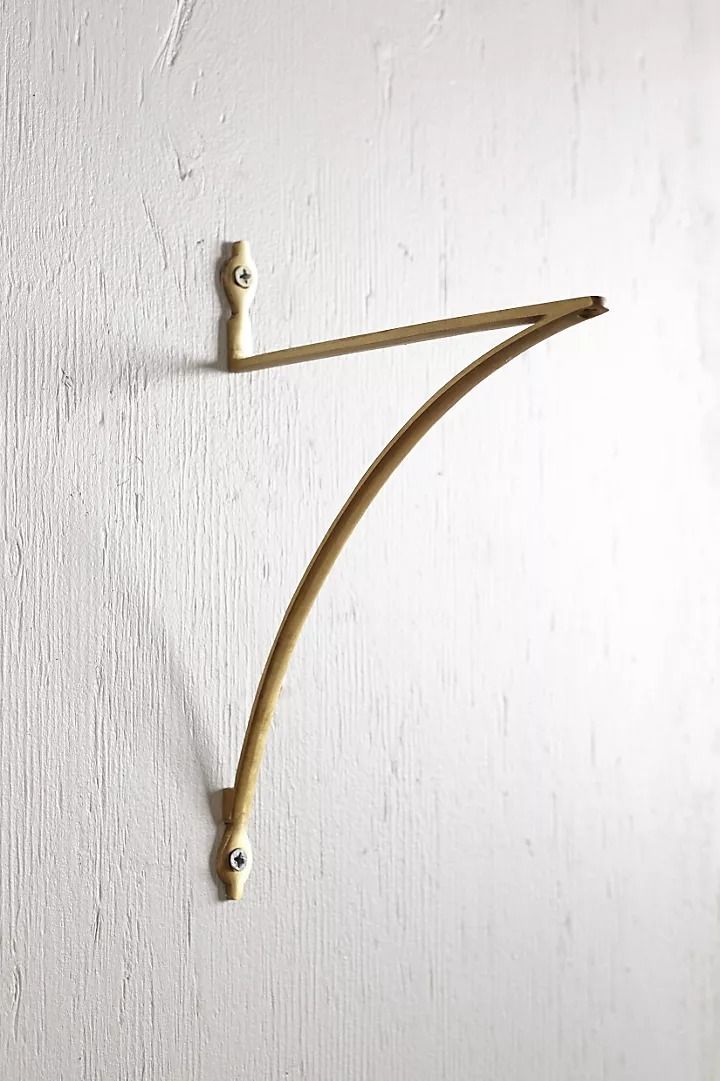 a white wall with a pair of wooden hooks attached to it's side,