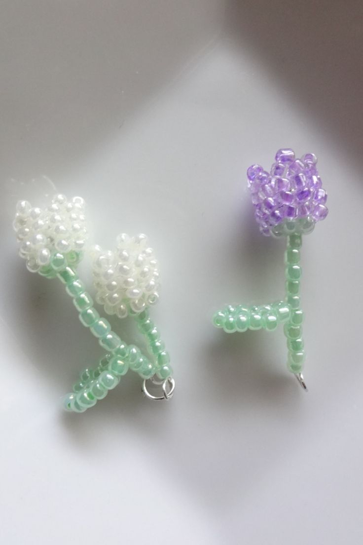 two beaded flowers sitting next to each other on top of a white countertop