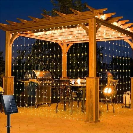 an outdoor gazebo with string lights on it and a grill in the back ground