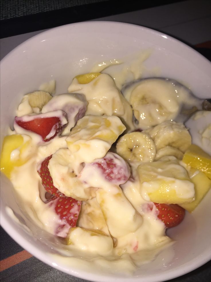 a white bowl filled with bananas and strawberries