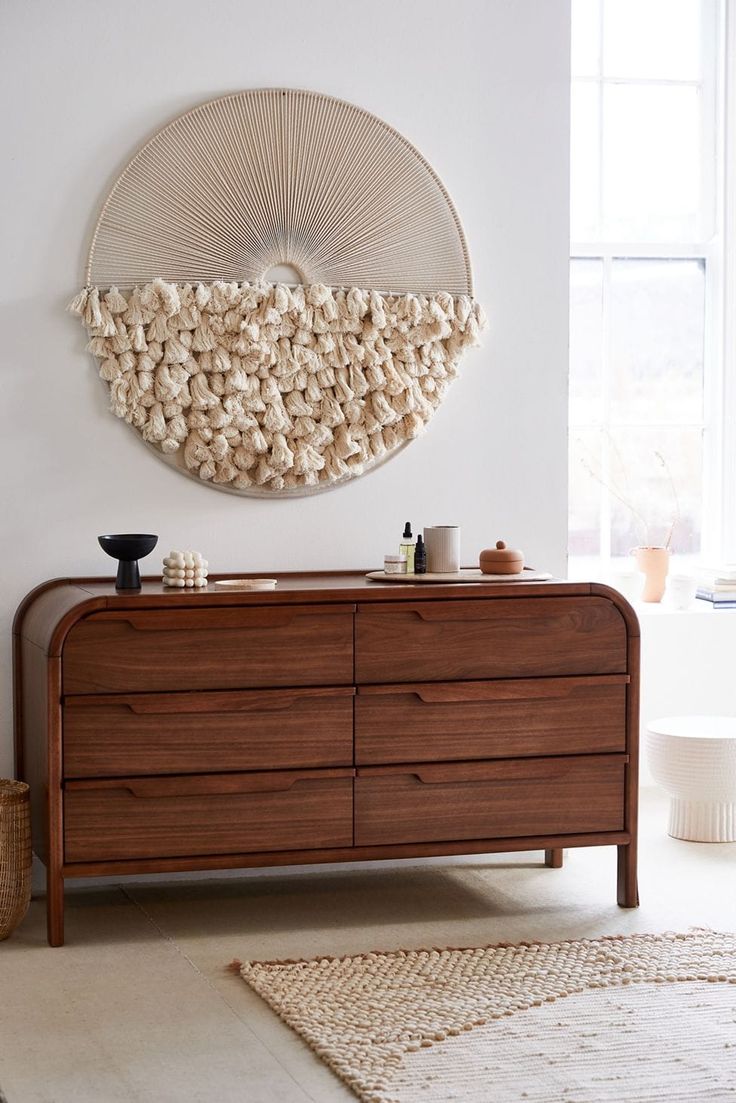 a wooden dresser sitting next to a window in a room with a rug on the floor