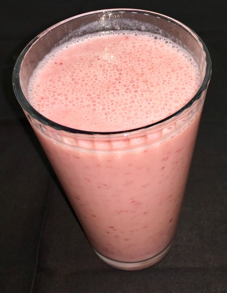 a glass filled with pink liquid sitting on top of a table