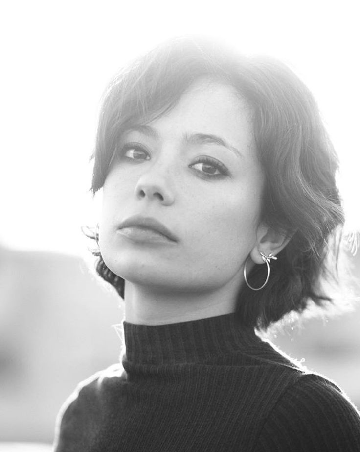 a black and white photo of a woman with earrings on her head looking off to the side