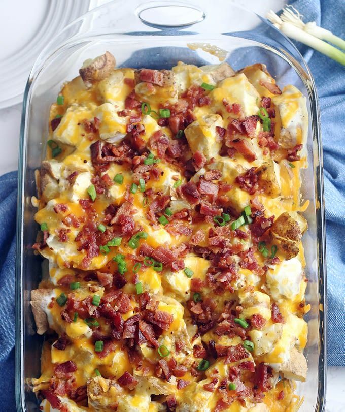 a casserole dish with eggs, bacon and green onions in it on a blue towel